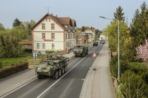 Militärfahrzeuge fahren durch ein Dorf