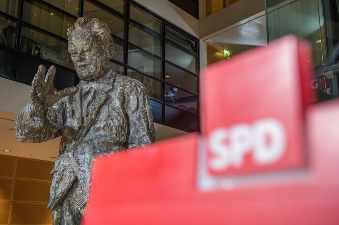 Die Skulptur Willy Brandts steht im Willy-Brandt-Haus hinter einem Logo der SPD