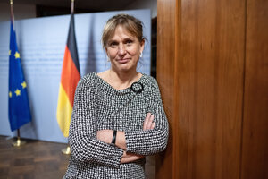 Frau mit verschränkten Armen vor Deutschland- und EU-Flagge