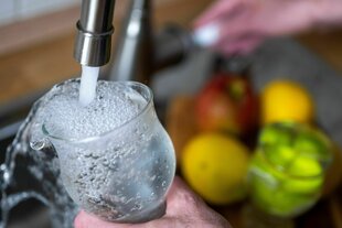 Tinkwasser läuft aus dem Wasserhahn in einer Küche in ein Glas