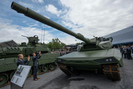 Männer in Anzügen fotografieren einen Panzer