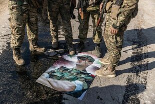 Bewaffnete syrische Oppositionskämpfer stellen ihre Füße auf ein Plakat mit einem Foto des syrischen Präsidenten Baschar al-Assad