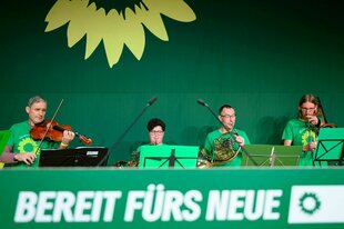 Eine Kapelle spielt auf dem grünen Podium über dem eine gemalte Sonnenblume prangt und der Slogan: Bereit fürs Neue zu sehen ist