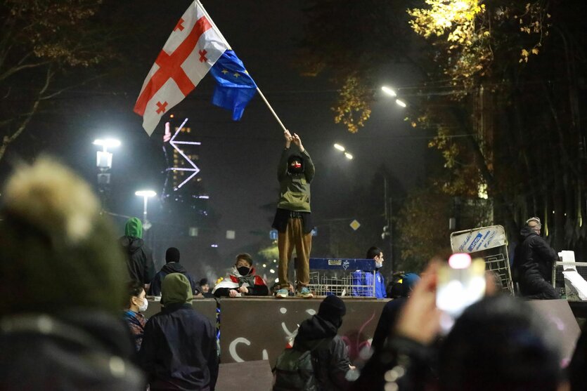 Ein Demonstrant steht mit georgischen National- und EU-Flaggen während einer Kundgebung vor dem Parlamentsgebäude