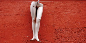 Beine einer Schaufensterpuppe vor roter Wand