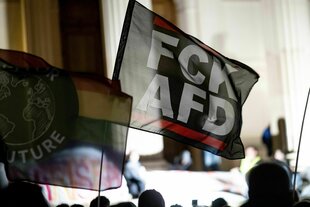 Demonstrierende gegen rechts halten eine Fahne hoch. Auf der steht: "FCK AFD"