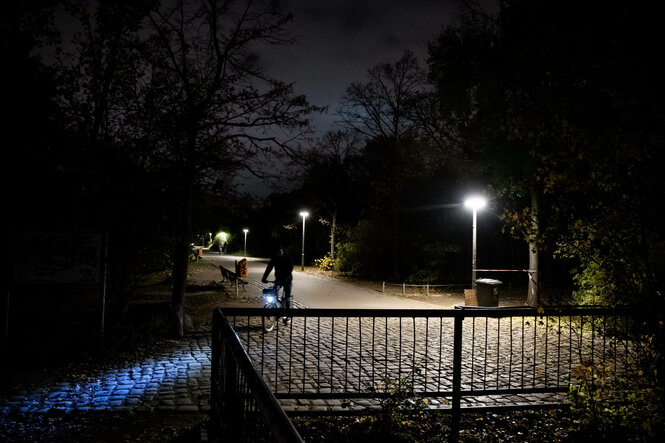 Ein Fahrradfahrer fährt auf einem beleuchteten Weg durch einen dunklen Park