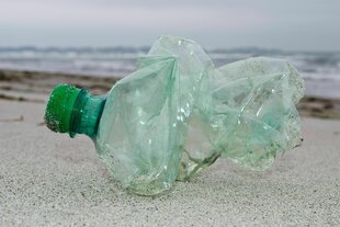 Am Strand liegt eine Flasche aus Kunststoff