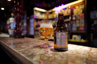 Ein Bierglas und eine -flasche stehen auf einem Tresen