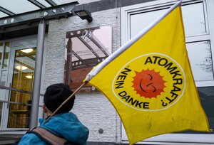 Eine Demonstrantin mit einer ?Atomkraft? - Nein Danke?-Fahne steht vor dem Oberverwaltungsgericht.