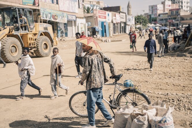 Ein Mann mit einer Schirmmütze mit der Flagge der Region Tigray überquert am 24. Mai 2024 mit seinem Fahrrad eine neu gebaute Straße in Mekele