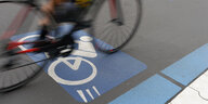Verwischter Radfahrer quert ein Verkehszeichen Radschnellweg auf der Straße