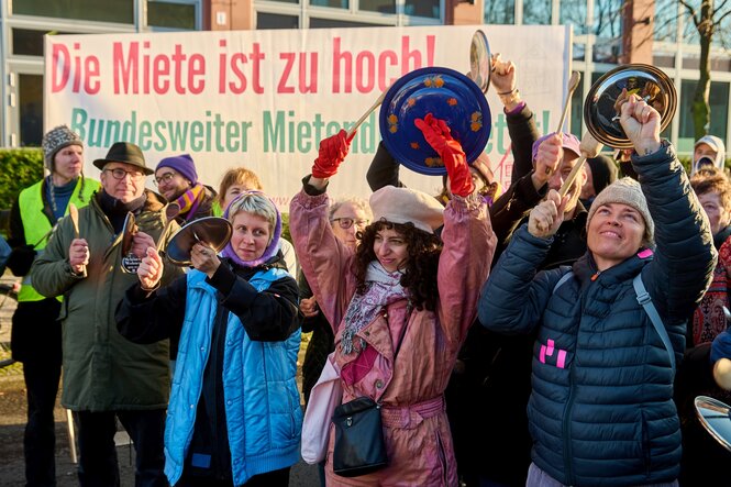 Auf einer Mieten-Kundgebung schlagen Menschen mit Kochlöffeln auf Topfdeckel