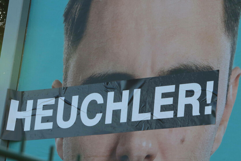 Auf einem Plakat sind die Augen eines Mannes überklebt mit dem Schriftzug "Heuchler"