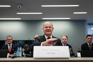 Olaf Scholz sitzt hinter dem Tisch eines Sitzungssaals