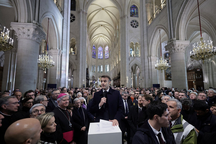 Macron spricht in der kathdrale Notre Dame umgeben von einer Menschenmenge