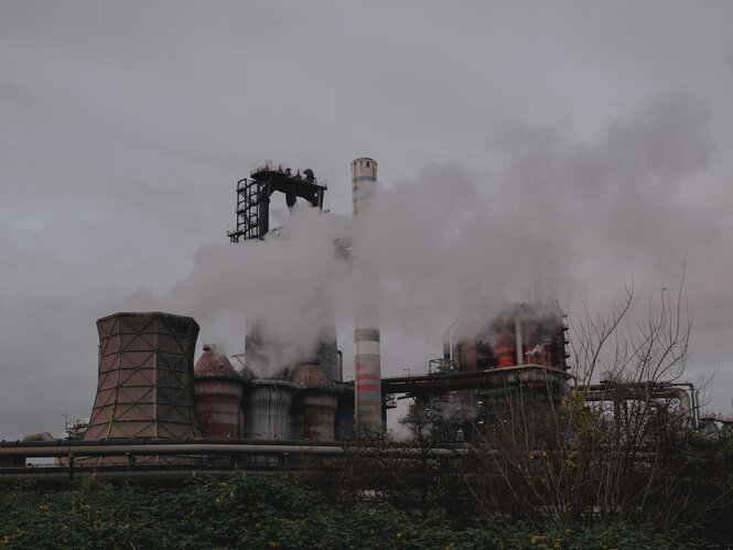 Die rauchenden Schlote und Kessel einer Fabrik