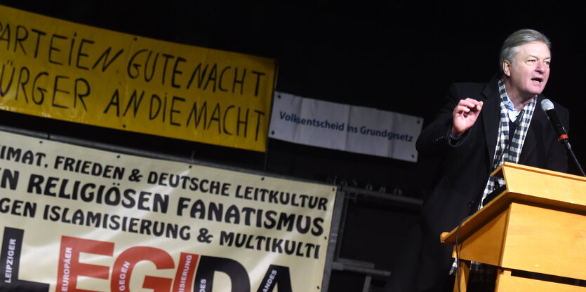 Jürgen Elsässer am Rednerpult neben Legida-Banner