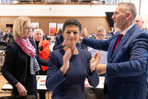 Eine Frau und ein Mann im Begriff, sich zu umarmen, davor klatscht eine Frau in die Kamera