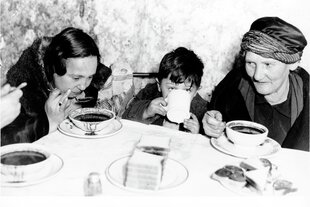 Ein Junge und zwei Frauen um einen Tisch. Sie essen und trinken