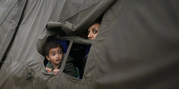 Ein Kind schaut aus einem Zelt