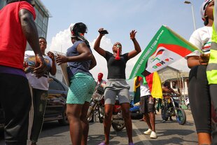 Auf der Straße feiern und tanzen Menschen mit Fahnen