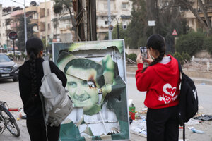 Frauen fotografieren ein zerstörtes Assad Foto