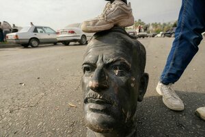 Ein Mann tritt auf eine Kopfstatue des Vaters von Baschar al-Assad