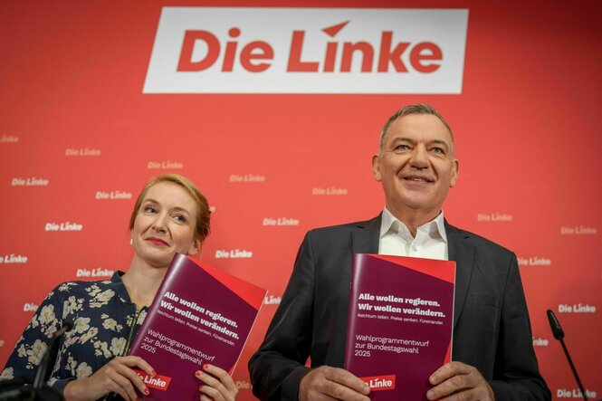 Die Linken-Parteivorsitzenden Ines Schwerdtner und Jan van Aken halten ihre Wahlprogramm in die Kamera