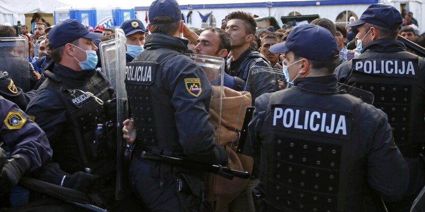 Polizisten stehen vor Menschen und drängen sie zurück