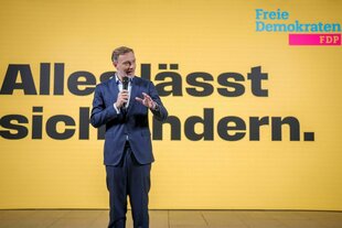 Christian Lindner steht vor einem Wahlplakat der FDP