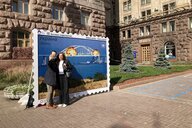 Zwei Menschen fotografieren sich in Kyiw vor einer großen Briefmarke zur Sprengung der Krim-Brücke