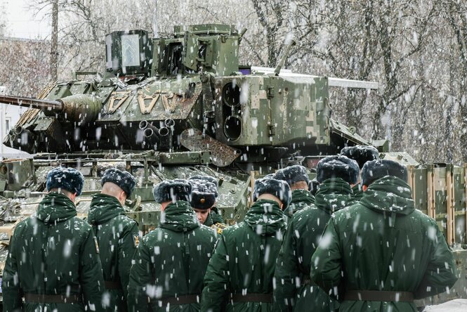 Russische Soldaten stehen bei starkem Schneefall vor einem Kampfpanzer