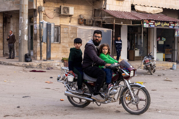 Ein Mann und zwei Kinder fahren mit einem Motorrad durch die syrische Stadt Aleppo