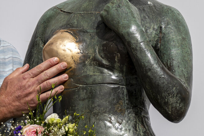 Eine Hand berührt die abgegriffene Brust einer Bronzestatue