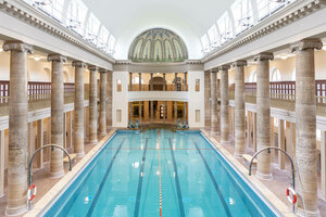 Stadtbad Neukölln im Mai 2021: menschenleeres blaues Schwimmbecken mit Steinsäulen rechts und links, Eingangskuppel Decke mit Mosaik