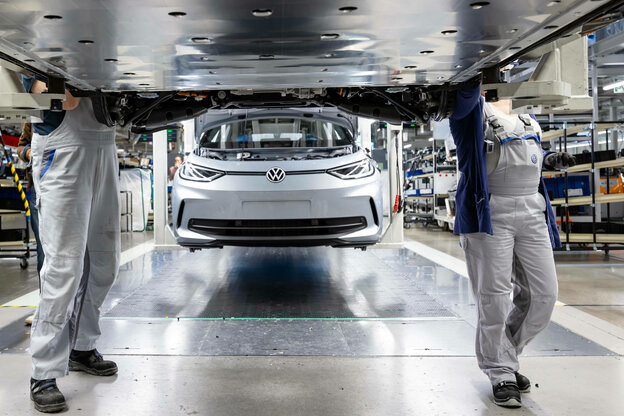 MitarbeiterInnen arbeiten am Unterboden mit der Batteriehalterung im VW-Werk Zwickau