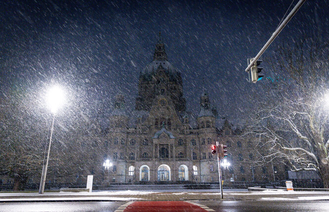 Das Neue Rathaus in Hannover im Halbdunkel bei Schneetreiben.