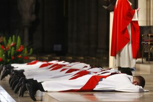 Demütig liegen junge Priester auf dem Boden der Kathedrale von Notre Dame