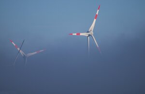 Zwei Windräder, die halb im Nebel verschwunden sind