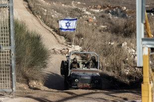 Militärfahrzeug mit drei Soldaten und aufgepflanzter israelischer Flagge fährt auf einer Landstraße