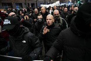 Schwarz gekleidete und glatzköpfige Demonstranten, einer zeigt das "White Power"-Symbol