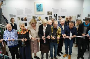 Menschen stehen bei einer Museeumseröffnung an einem rosafarbenem Band und schneiden es zur Feier durch