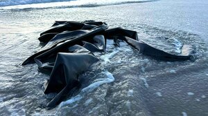 Ein schwarzes, kaputtes Schlauchboot liegt am Strand