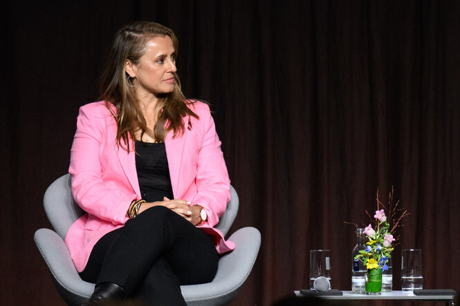 Jagoda Marinić sitzt bei einer Podiumsdiskussion auf einer Bühne.