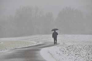 Ein Mann mit Regenschirm in Schneelandschaft