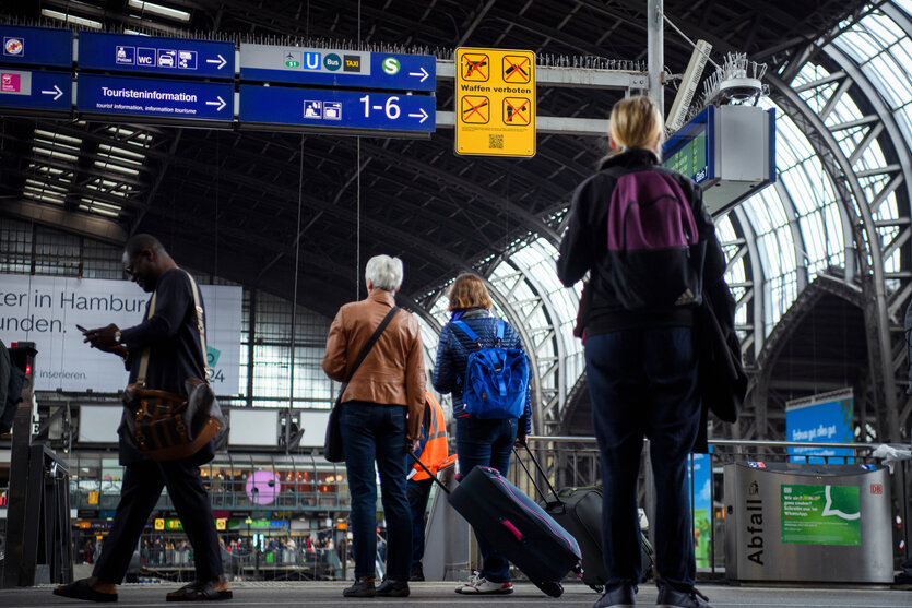 Reisende mit Gepäck stehen an einer Treppe am Hamburger Hauptbahnhof