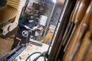 Eine Auszubildende arbeitet an einer Drechselbank in einem Bremer Betrieb. Im Vordergrund einige Werkzeuge, im Hintergrund die Werkstatt