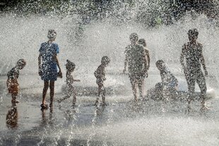 Eine Gruppe von Kindern spielt in Wasserfontänen