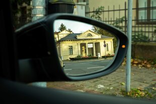 Ein Foto zeigt das Torhaus des Photomuseums im Rückspiegel eines Autos